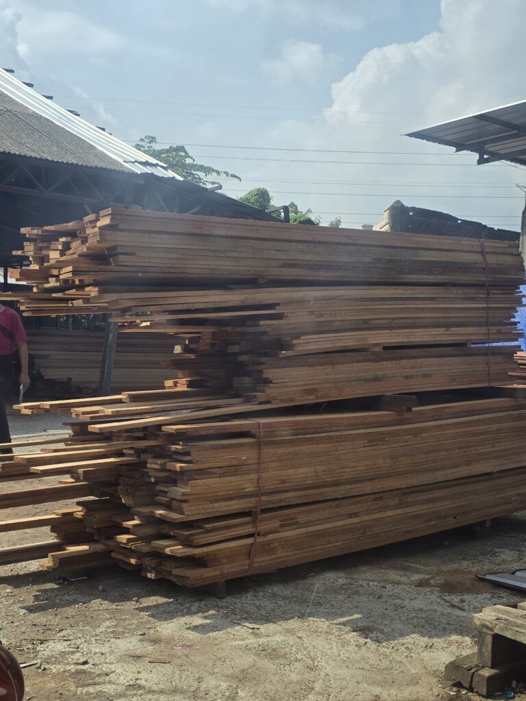Tumpukan balok dan papan kayu di area penyimpanan